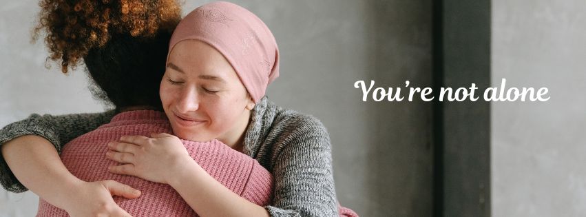 Photo of two women hugging and the text, 'You're not alone'.